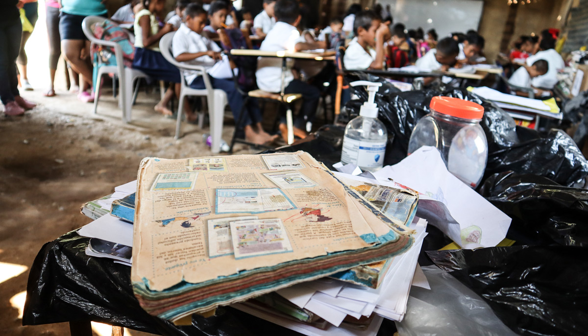Estudiantes en una escuela muy pobre reciben sus clases con textos muy viejos y rotos